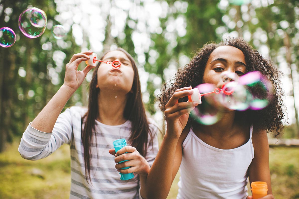 Two girls blowing bubbles in summer weather