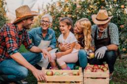 Multigenerational family in an apple orchard smiling