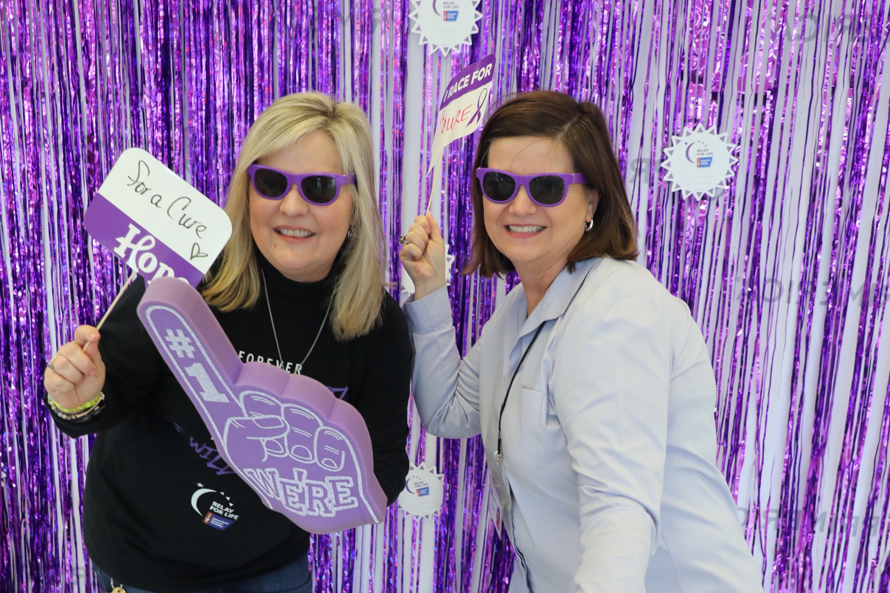 Two female Primerica employees with festive gear posing in front of Relay for Life backdrop