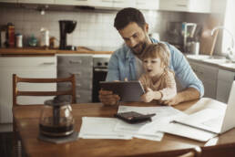 Photo of a father budgeting with daughter on lap