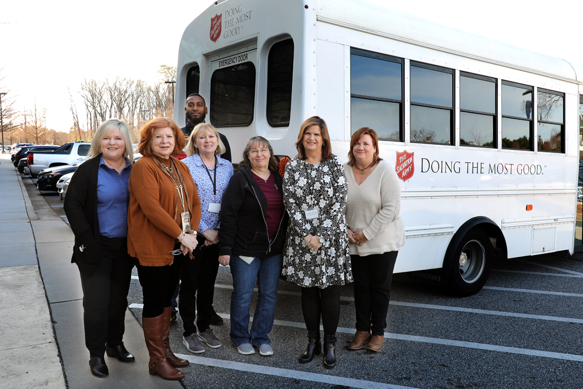 Photo of home office employees posing in front of a Salvation Army truck