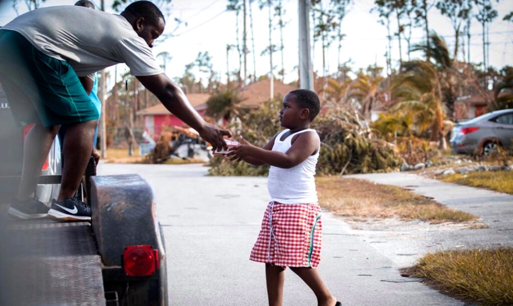 Photo of a man on truck giving an item to a Bahamian child