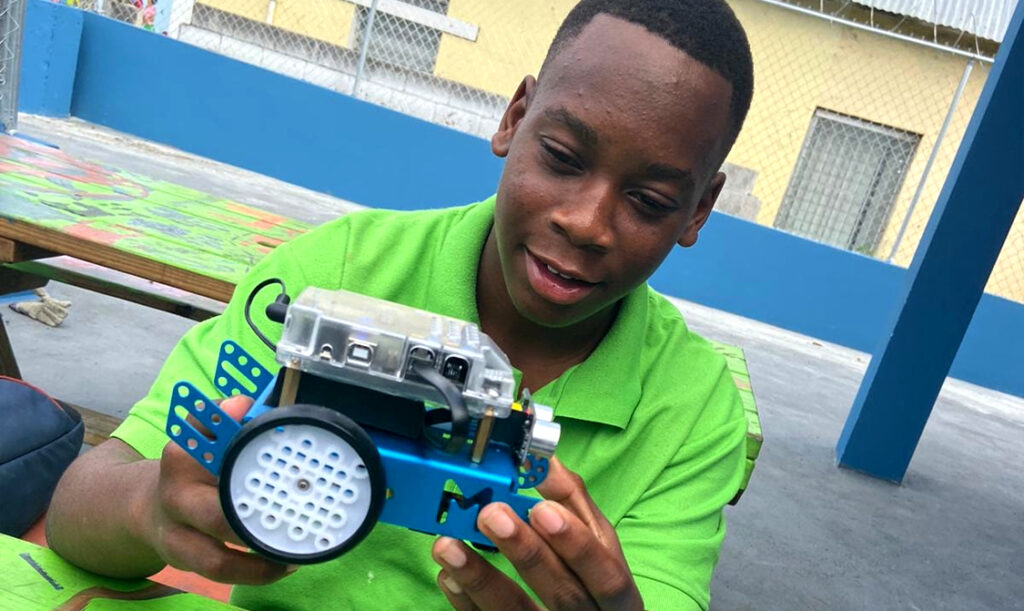 Photo of teenage Bahamian boy holding an mechanical toy