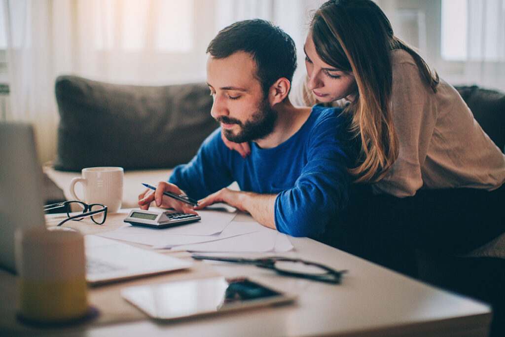 Couple sitting in their living room and checking their finances