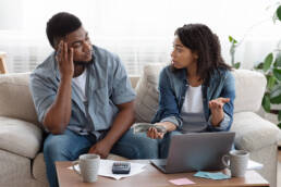 African American couple accounting family budget at home, wife scolding her husband for overspending and lack of money